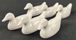 Conjunto de seis descansos para talheres em porcelana branca esmaltada, modelados como patos. Medidas: 5 x 9 cm cada.
