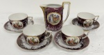 VISTA ALEGRE, PORTUGAL. Conjunto para chá em porcelana, composta por leiteira e quatro xícaras com respectivos pires. Decoração em fundo vinho marmorizado, com reservas representando cenas galantes em policromia, realçadas por frisos dourados.  Manufatura no verso. A leiteira mede 14 x 13 cm. Apresenta desgastes e um pires com restauro.