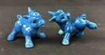Par de pequenas esculturas em porcelana esmaltada na cor azul, modeladas como filhotes de veado em movimento, com detalhes pintados. Medidas: 8 x 7 cm cada.