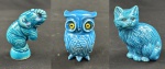 Conjunto de três pequenas esculturas em porcelana esmaltada na cor  azul-turquesa, representando gato, coruja e elefante, com detalhes moldados em relevo. A coruja apresenta olhos de vidro, e o elefante possui acabamento craquelado. Medidas: gato 13 x 7 cm; coruja 9 x 4 cm; elefante 7 x 3 cm