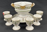 FRANÇA. Conjunto em porcelana francesa, composto por molheira com presentoir fixo e seis porta-ovos. Decoração em arabescos verdes e dourados, com monograma coroado e frisos dourados. Total: 7 peças. Identificação da maison parisiense na base. Medidas: molheira 11 x 17 x 16 cm; porta-ovos 6 x 5 cm cada. A molheira apresenta desgastes na douração, e um porta-ovos apresenta bicado.