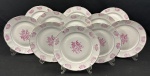 Barão do Rio Branco. Onze pratos rasos em porcelana branca esmaltado com decoração floral na cor rosa, filetes em ouro e bordas levemente recortadas. Manufatura no verso. Medindo: 24 cm. 1 com fio de cabelo.