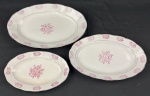 Barão do Rio Branco. Três travessas em porcelana branca esmaltado com decoração floral na cor rosa, filetes em ouro e bordas levemente recortadas. Manufatura no verso. Medindo: 18 x 29 cm, 3 x 22 x 34 cm e 4 x 25 x 39 cm. 1 com leve mancha e craquelê.