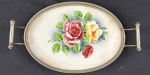 Bandeja ovalada, com alças, em faiança europeia, decorada com pintura floral. Guarnições em metal. Pequenas marcas do tempo. Medindo: 5 x 19 x 31 cm.