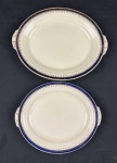 GRINDLEY - Duas travessas em faiança inglesa no tom creme, com decoração geométrica, filete em azul cobalto e detalhes em ouro.  Medindo: 27 x 21,5 cm e 32 x 26 cm.  Uma apresenta fio de cabelo.