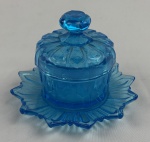 Manteigueira em vidro prensado na cor azul. Medindo: 12 x 8 cm. Tampa apresenta bicados.