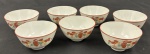 CHINA. Conjunto de sete pequenas tigelas em porcelana, com decoração floral em policromia, predominando tons de vermelho, verde e amarelo, e frisos vermelhos nas bordas. Uma apresenta fio de cabelo. Medindo: 5 x 9 cm, cada.