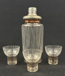 Conjunto vintage composto por 1 coqueteleira e 3 copos, confeccionados em vidro transparente e decorados com delicadas linhas verticais e detalhes em pintura dourada. Medindo: 23 cm e 7 x 7 cm. Bicado na borda da coqueteleira e em uma taça.