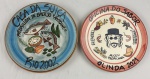 Dois pratos decorativos em cerâmica pintados à mão, alusivos ao restaurante  Boa Lembrança, datados de "Rio 2002 " e " Olinda 2021". Medindo: 26 cm.