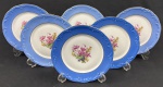 Schmidt. Seis pratos para sobremesa em porcelana nacional, esmaltado e policromado, decoração em relevo, borda azul e medalhão central de flores. Manufatura no verso. Medindo: 18 cm.
