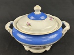 Schmidt. Sopeira em porcelana nacional, esmaltado e policromado, decoração em relevo, borda azul e medalhão central de flores. Manufatura no verso. Medindo: 21,5 x 30 cm. Bicado e fios de cabelo.
