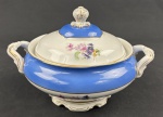 Schmidt. Terrina em porcelana nacional, esmaltado e policromado, decoração em relevo, borda azul e medalhão central de flores. Manufatura no verso. Medindo: 17 x 27 cm.