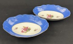 Schmidt. Duas saladeiras em porcelana nacional, esmaltado e policromado, decoração em relevo, borda azul e medalhão central de flores. Manufatura no verso. Medindo: 6 x 20 x 29 cm. (1 com lasca).