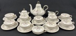 SALER. Serviço para chá em porcelana esmaltada, ricamente decorada em policromia, em tons suaves, com galhos e folhagens, bordas com friso a ouro: bule, cremeira, açucareiro, nove xícaras com pires. Marca do fabricante na base. Medindo: Bule: 20x25 / leiteira 7x14x11 / manteigueira 10x14x13 cm ( alça colada e fio de cabelo) 10 xícaras de chá com 9 pires