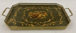 Bandeja retangular com fundo aglomerado. Decoração, nas cores marfim e marrom, representando instrumentos musicais, partitura, flores e arabescos. Galeria e alça de metal amarelo vazado (oxidado). Med. 41,5 x 23 cm (C x L).