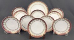Schmidt. Conjunto para sobremesa em porcelana branca, com larga faixa furta-cor, borda em tom vinho e profusa ornamentação dourada. Composto de prato para bolo e 10 pratos para sobremesa. Manufatura no verso. Medidas: 27 cm e 19 cm. 1 com restauro não profissional.