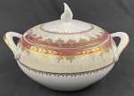 Schmidt. Terrina em porcelana branca, com larga faixa furta-cor, borda em tom vinho e profusa ornamentação dourada. Manufatura no verso. Medidas:17 x 29 cm.