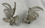Par de esculturas, representando galos em metal prateado. (desgastes). Medindo: 27 x 19 cm e 23 x 22 cm