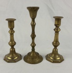Três castiçais em metal dourado. (desgastes). Medindo: 17 cm, 18,5 cm e 21,5 cm.
