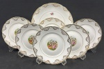 Real. Conjunto para sobremesa em porcelana nacional esmaltada e policromada, decorada com rica douração, medalhão central de cena de galanteio e flores policroma. Bordas onduladas e filetadas a ouro. Composto de prato para bolo e 6 pratos para sobremesa. Manufatura no verso. Medindo: 26 cm e 18 cm.