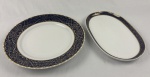 Trahl,Style Bavaria. Duas travessas em porcelana, esmaltada na cor branca, borda em azul cobalto com rica decoração de arabescos e volutas em ouro. Manufatura no verso. Medindo: 33 x 21 cm e 32 cm. Uma com bicado.
