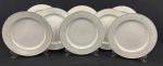 Schmidt, Voyage. Oito pratos rasos em porcelana esmaltada na cor branca, borda decorada e filetes em prata. Manufatura no verso. Medindo: 25,5 cm.