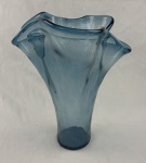 Grande vaso decorativo em vidro artístico na tonalidade azul, com corpo alongado e borda superior ondulada em formato orgânico, apresentando acabamento translúcido com pequenas bolhas internas. 41 x 34 cm de altura.
