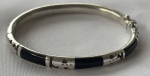 Pulseira rígida em prata de lei, tipo algema, com apliques pretos e desenhos vazados. Peso: 10,4 g.
