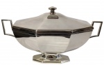 ST. JAMES. Imponente e elegante sopeira em metal espessurado a prata, com corpo bojudo e facetado, duas alças laterais vazadas. Tampa abaulada com frisos escalonados e puxador geométrico. Peça marcada St. James. Medidas: 47 X27 X 25,5 cm.