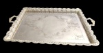 Grande e imponente bandeja retangular em metal espessurado a prata, com centro gravado por motivos de volutas e arabescos, borda recortada, vazada e ricamente lavrada, ladeada por duas alças. Medindo: 5 x 72 x 48 cm.
