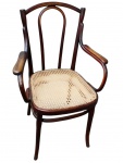 THONET. Cadeira de braços em madeira curvada, com espaldar vazado, braços sinuosos, assento em palhinha sintética e pés arqueados, unidos por travessas. Apresenta marcas do tempo . Medindo: 92 x 59 x 46 cm.