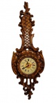 Antigo relógio de parede em madeira entalhada, com rica ornamentação de inspiração Barroca, composta por volutas, folhagens, elementos vazados e relevos. Mostrador circular com algarismos romanos e mecanismo a pilha. Estrutura de madeira em excelente estado de conservação. Funcionamento não testado, vendido no estado. Medindo: 97 x 33,5 cm.