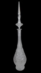 Grande e imponente garrafa em cristal translúcido, com corpo bojudo, longo gargalo e rica lapidação geométrica, composta por losangos, pontas de diamante e motivos estrelados. Acompanha alta tampa facetada e pontiaguda. Medindo: 86 x 19 cm de diâmetro. 