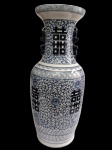 CHINA. Grande e imponente vaso em porcelana, de corpo alongado e colo alto com boca alargada, decorado em azul e branco com motivos florais, faixas geométricas e símbolos orientais de dupla felicidade. Apresenta alças laterais estilizadas em relevo. Medidas: 60 x 25 cm.