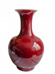 Grande vaso em porcelana, de corpo globular e longo colo cilíndrico, revestido por esmalte monocromático vermelho-sangue-de-boi (sang-de-boeuf). Medidas: 39 x 23 cm.