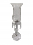 Antigo castiçal em vidro, com base recortada, coluna facetada e bobeche ornamentado por pingentes em forma de lança. Cúpula alta e removível em vidro translúcido, com borda ondulada e decoração floral fosqueada. Altura: 51,5 cm.