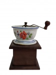 Antigo moedor manual de café, com estrutura e gaveta coletora em madeira, recipiente superior em porcelana decorada com motivos florais policromados e frisos azuis. Mecanismo e manivela em metal, com empunhadura de madeira. Apresenta marcas do tempo e do uso. Medidas: 16 x 12 x 12 cm.