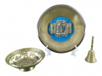 METAL DOURADO e BRONZE, três (3) peças, sendo: A) um (1) prato decorativo em metal dourado com ricos relevos florais e medalhão central azul, apresentando as Tábuas da Lei e inscrição Jerusalem, mossa na borda, medindo 24,5cm, B) uma (1) pequena tigela em metal dourado com decoração floral policromada, medindo 5,5x16,5cm e C) uma (1) sineta confeccionada em bronze com pega torneada, medindo 12,5cm.