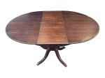 MOBILIÁRIO, uma (1) mesa de jantar extensível confeccionada em madeira escura, com tampo circular em lâminas, inserção de folha central removível, assume formato oval, apoiado sobre coluna central torneada e base composta por quatro pés curvos em caneluras, apresenta falhas na lâmina, aberta medindo 77x147,5x110cm e fechada 110cm de diâmetro.