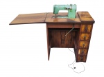 COLECIONISMO, uma (1) máquina de costura da manufatura suíça ELNA, modelo Supermatic, em estrutura metálica com acabamento na tonalidade verde, instalada em móvel de madeira com tampo extensível e compartimento próprio para embutimento da máquina, apresentando cinco (5) gavetas laterais com puxadores metálicos ornamentados. A ELNA, tradicional fabricante suíça fundada na década de 1940, destacou-se pela produção de máquinas de costura de design moderno e soluções técnicas inovadoras. Apresentam sinais de uso, marcas do tempo, gabinete com falhas nas lâminas e leves desgastes, vendidos no estado da foto.