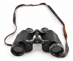 INSTRUMENTO ÓPTICO, um (1) binóculo CARL ZEISS JENA, modelo DELTREM 8x30, corpo metálico preto com revestimento texturizado e regulagem central de foco, acompanhado de correia em couro. Número de série 169528. Peça com sinais acentuados de uso, riscos, perdas de pintura, oxidação e desgaste no revestimento e na correia, medindo 11,5x16cm.