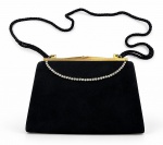 ACESSÓRIO FEMININO, uma (1) bolsa de festa, confeccionada em tecido aveludado preto, fecho superior em metal dourado, ornamentação frontal com fileira de strass incolor e alça longa em cordão trançado preto. Apresenta sinais de uso e oxidações nas ferragens, medindo 15,5x21cm.