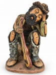 MANOEL BERNARDO, uma (1) escultura confeccionada em barro cozido policromado representando músico com pintura policromada, medindo 23cm de altura.