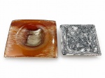 VIDRO e FAIANÇA, dois (2) cinzeiros para charutos, sendo: A) 1 confeccionado em vidro soprado na tonalidade âmbar, medindo 23,5x23,5cm e B) ZEKA ALBUQUERQUE, "Matagal", 1 confeccionado em faiança vitrificada com pintura de matagal em monocromia na tonalidade preta, bicados na borda, medindo 19x19cm;