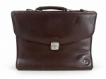 BAGAGIO, uma (1) pasta executiva para documentos, em material sintético na cor marrom, com alça de mão, fecho metálico frontal, compartimentos internos, divisórias e bolso com zíper. Apresenta emblema metálico da marca BAGAGIO. Peça com sinais de uso, desgastes, marcas do tempo e avaria em uma das extremidades inferiores. No estado. Medindo 30x40cm.