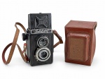 FOTOGRAFIA, uma (1) câmera fotográfica analógica vintage, marca LUBITEL-2, de fabricação soviética, modelo reflex de duas objetivas (TLR), para filmes de médio formato 120, com visor superior e controles manuais de foco e exposição. Corpo na cor preta, com detalhes metálicos. Acompanha estojo original marrom e alça de transporte arrebentada. Apresenta sinais de uso, desgastes e marcas do tempo. Funcionamento não testado. No estado.