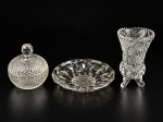 VIDROS, três (3) peças confeccionadas em vidro translucido, sendo: A) 1 pequena bomboniere com moldagem bico de jaca, medindo 11x9,5cm, B) 1 prato circular com moldagem geométrica, vestígios de pintura e bicado na base, medindo 16cm e C) 1 vaso confeccionado em demicristal com rica lapidação geométrica em baixo relevo com borda dentada, medindo 14x8,5cm.