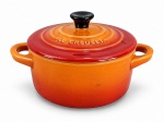 LE CREUSET, uma (1) mini caçarola confeccionada em cerâmica refratária de origem francesa na tonalidade laranja com pega da tampa na tonalidade preta, medindo 7,5x14x10cm.