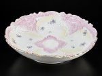 PORCELANA, uma (1) fruteira confeccionada em porcelana na tonalidade branca, moldada por elementos vegetalistas em relevo na pasta, pintura de flores e folhagens em policromia e degrade nas tonalidades rosa e amarela e borda filetada em ouro, medindo 6,5x25,5cm. Leves falhas na douração.