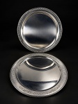 METAL INOX, duas (2) travessas redondas confeccionadas em aço inox, sendo: A) 1 EBERLE, com borda decorada em gomos torcidos, leves sinais de uso, medindo 38cm e B) TRAMONTINA, 1 cinzelada por elementos geométricos com borda em gomos torcidos, medindo 38cm. Sinais de uso.